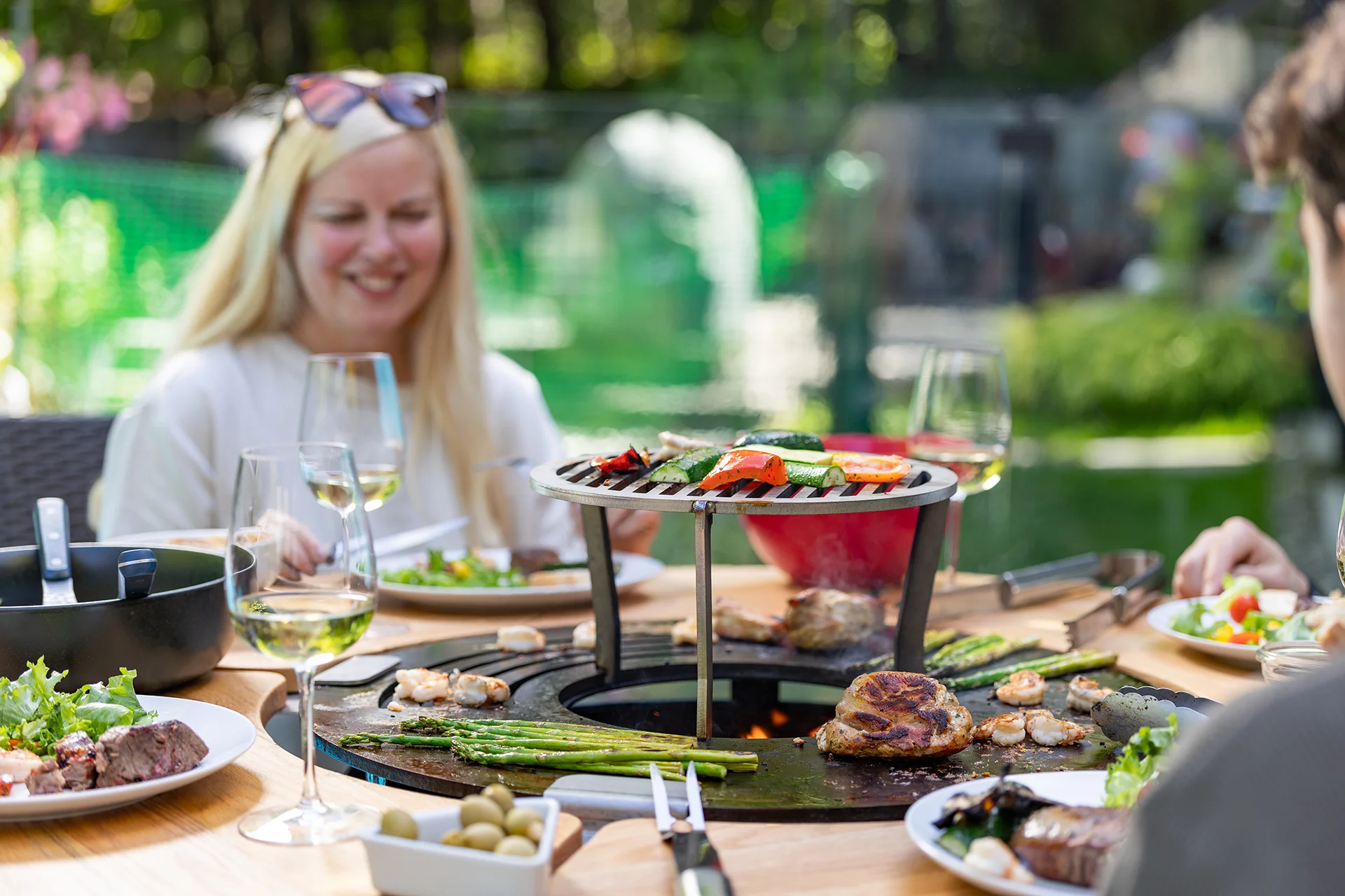 Repas convivial autour d’un brasero extérieur avec cuisson sur la terrasse